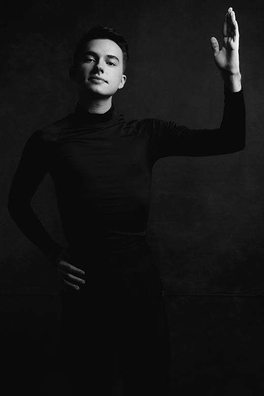 Dramatic black and white photo of Alejandro Gonzalez, man, in all-black rhythm dance attire